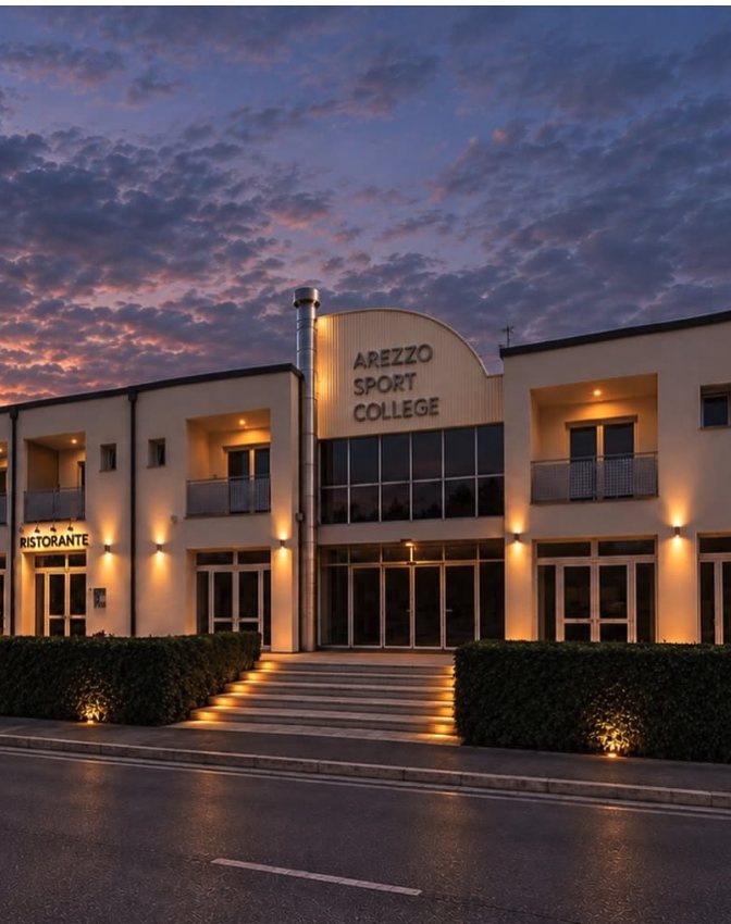 L'ingresso dell'ASC Hotel Arezzo Sport College al tramonto, con il ristorante illuminato